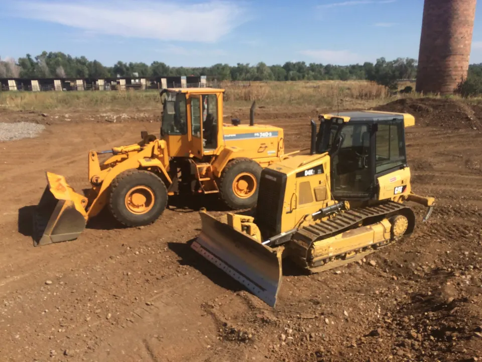 Yellow Hyundai wheel loader and CAT D4K dozer parked on a graded dirt pad